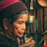 一位编辑的圆形头像占位图，背景是珊瑚色与青绿拼接的几何图案，人物正对镜头